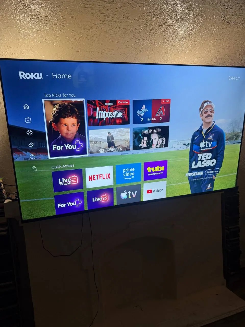 Roku smart TV interface displayed on 90 inch TV mounted above fireplace in Los Angeles
