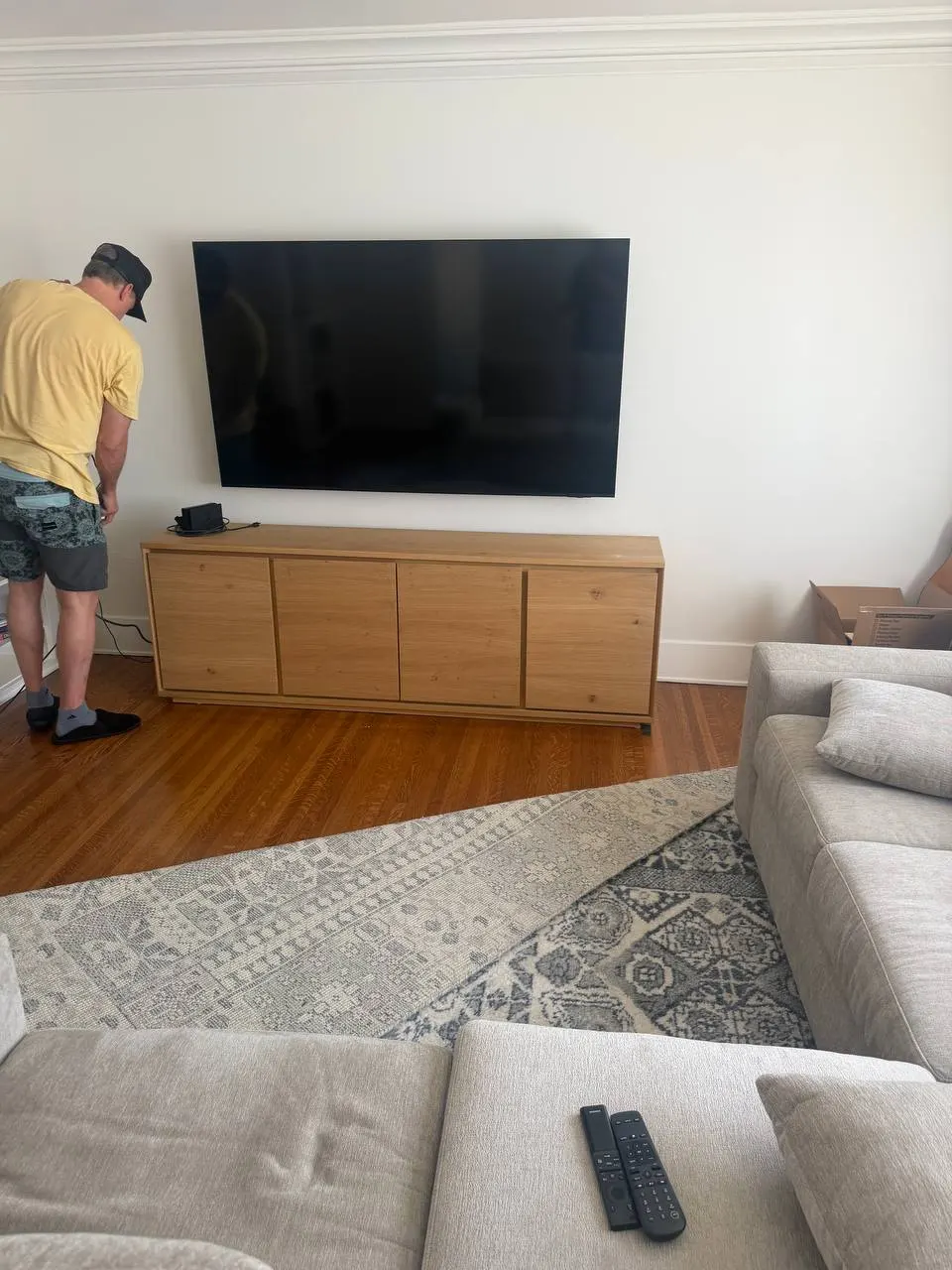 75-inch flat screen TV mounted on white drywall above wood credenza with hidden cables in Beverly Hills living room