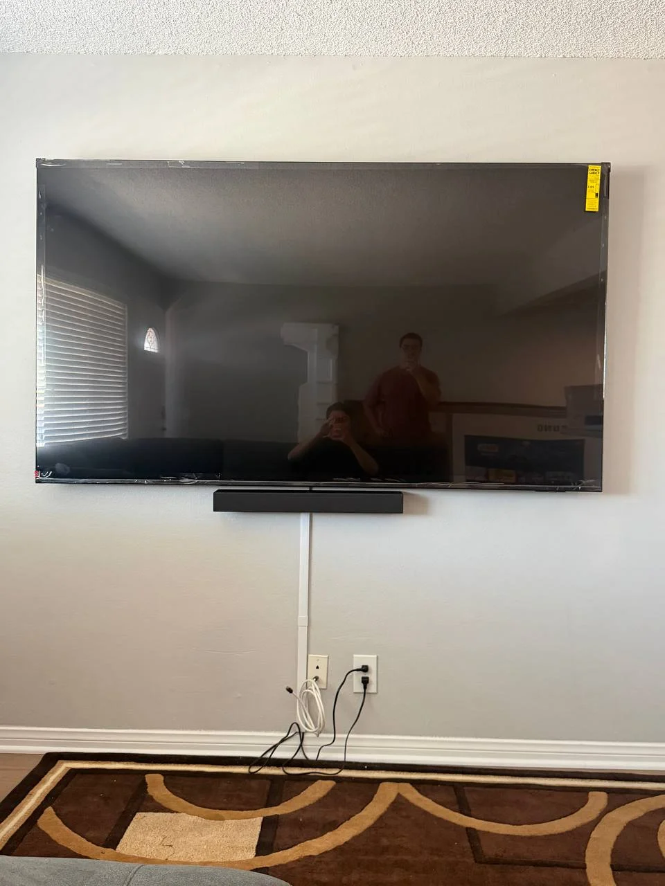 75-inch TV mounted on drywall in Los Angeles living room with visible cords before hidden wire service